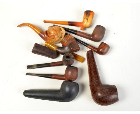 A collection of tobacco pipes including a meerschaum pipe carved with a bowl held in a claw and carved wood Turk's head.