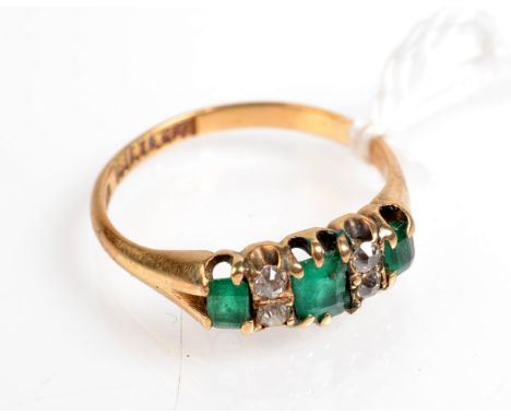 A late Victorian Glasgow hallmarked 18ct. gold ring set three emeralds and four diamonds.  Glasgow 1900.