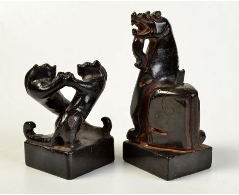 A Chinese black stone, possibly jade, seal carved with fighting lions, together with a similar animal carved seal.