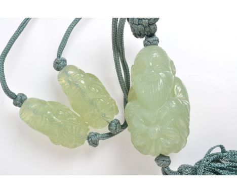 A Chinese necklace with a carved pendant drop in the form of a seated immortal also strung with two smaller beads, possibly j