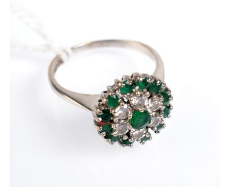 An 18ct. white gold ring with a peg set emerald and diamond target cluster. 