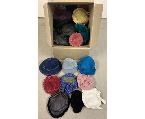 A large box of assorted vintage hats in varying colours and styles. 