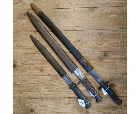 A 1907 pattern bayonet, in a leather scabbard, and two other bayonets with scabbards (3)