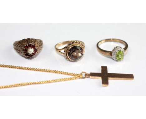 A 9ct gold cross with an attached gold plated chain, a 9ct gold smokey quartz set ring, a peridot and diamond set ring and a 