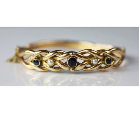 An untested sapphire and pearl set bangle, the hinged bangle set with three sapphires and two pearls, within openwork surroun