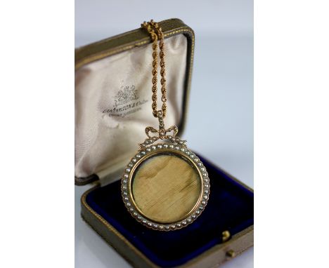 An Edwardian seed pearl set pendant and chain, the circular pendant with with split seed pearls and bow surmount, stamped '15