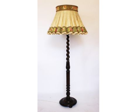 A 1920's carved oak standard lamp, with barley twist column, on circular base, with elaborate floral and brocade shade