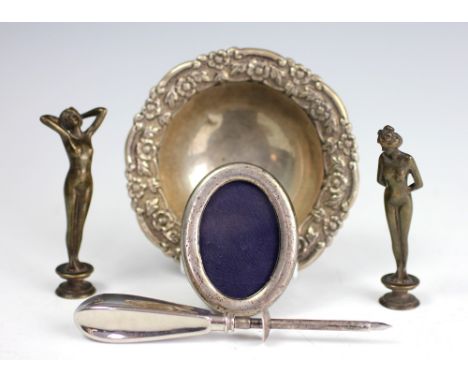 A silver tripod bowl, with florally embossed rim, stamped underside 'Silver' 12cm diameter, with two bronze pipe tampers mode