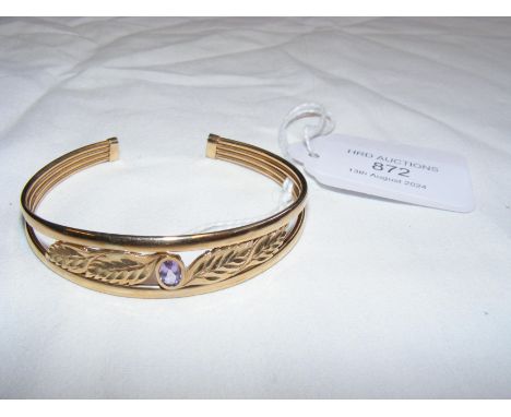 A 9ct bangle with leaf and central stone design