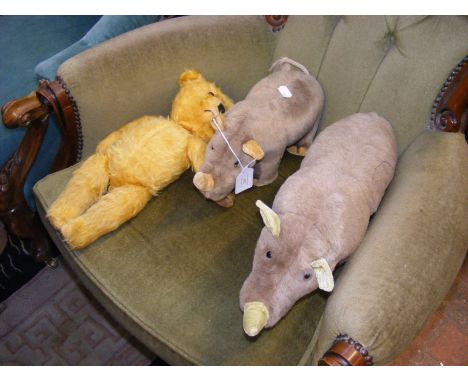 Two vintage Merrythought rhinos, together with an old straw filled teddy bear