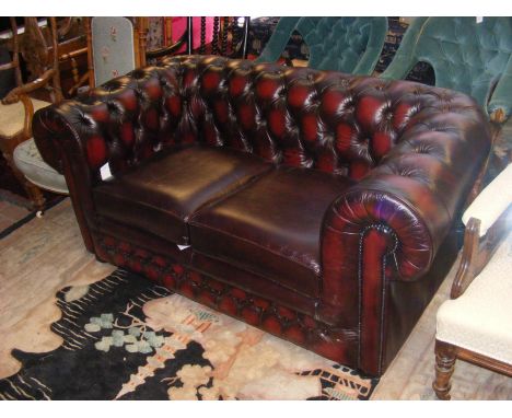 An oxblood red leatherette Chesterfield style sofa - width 160cms