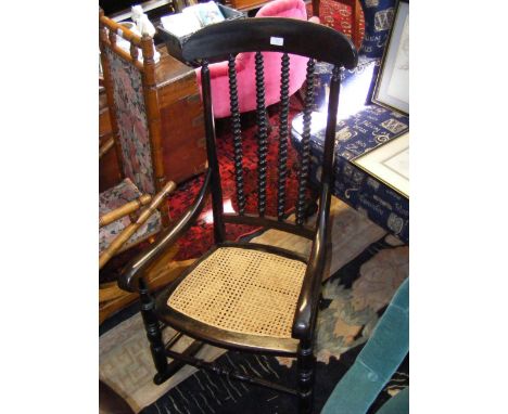 A dark wood rocking chair with bobbin back and cane seat