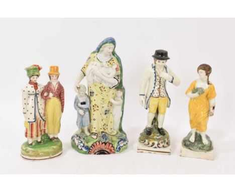 Four early 19th century English pottery figures, including a pearlware figure of Charity, a pearlware couple on an oval base,