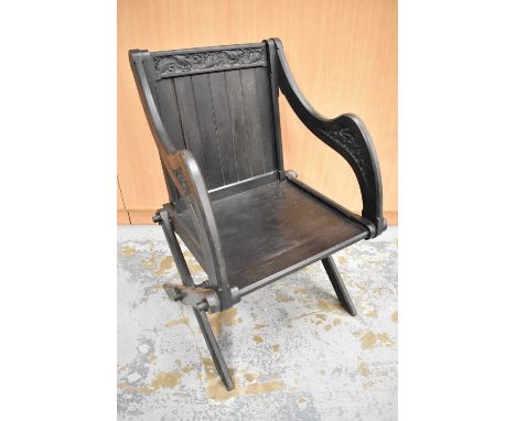 Victorian carved ebony Glastonbury chair, with scroll carved top and arms, stamped Holland &amp; SonsOne leg is a probably a 