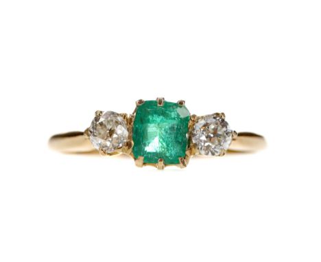 EMERALD AND DIAMOND RING set with a step cut emerald of approximately 0.48 carats flanked by two Old European cut diamonds to