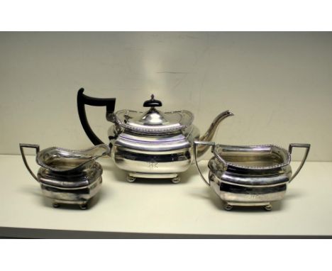 A silver three piece tea set by Walker and Hall, Sheffield 1921, comprising:- a teapot of compressed rectangular shape with m