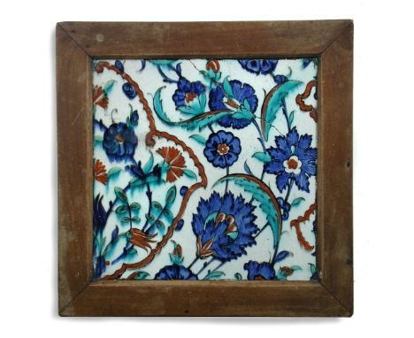 A 16th century Islamic Turkish Iznik tile in wooden frame painted with blue flowers, turquoise leaves and red details all on 