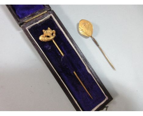 A fox head stick pin together with another depicting a bird taking flight, the first with a textured fox's mask above a hunti
