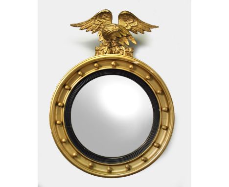 A Regency gilt framed convex wall mirror, with carved eagle cresting and ball decorated frame 66cm (26in)  Later gilt painted