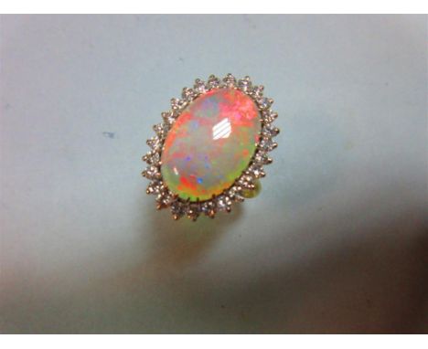 An opal and diamond cluster ring, the 17mm long oval cabochon opal, displaying good predominantly red and orange fire, in a b