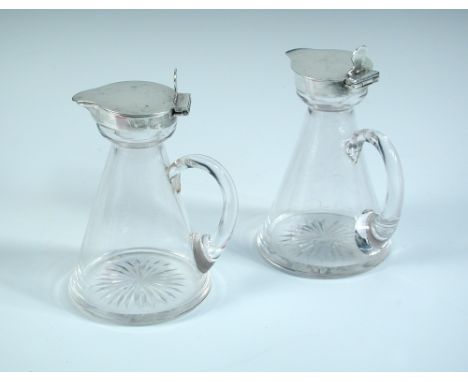 An Edwardian pair of silver mounted glass whisky noggins, the plain conical glass bodies each with silver mount and cover by 
