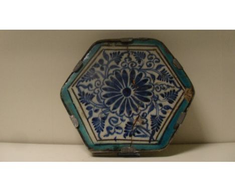A 15th century Islamic Mamluk hexagonal tile, the central blue rosette enclosed by foliage on a white ground and a turquoise 