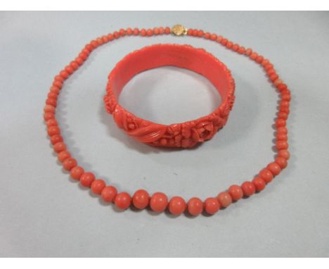 A graduated strand of coral beads and an early plastic carved 'coral' bangle, the necklace of graduated 5-8mm individually kn