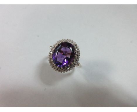 An amethyst and diamond ring, the oval mixed cut amethyst of good colour, claw set in a border of single cut diamonds, in whi