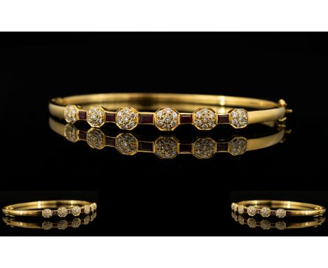 An 18ct Gold Diamond And Ruby Set Bangle Hinged yellow gold bangle set with five calibre cut rubies between six, seven stone 