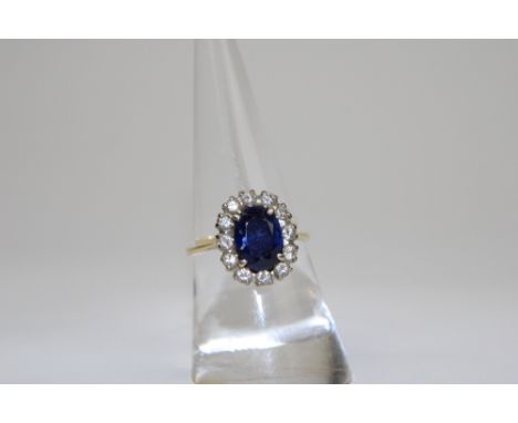 Sapphire and Diamond cluster ring, set with an oval sapphire framed by brilliant cut diamonds, stamped 18 .