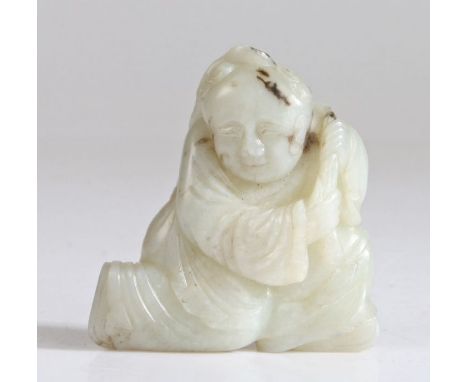 A Chinese jade carving of a boy, Qing Dynasty, 17th Century, white tone with black markings, carved as a boy immortal half kn