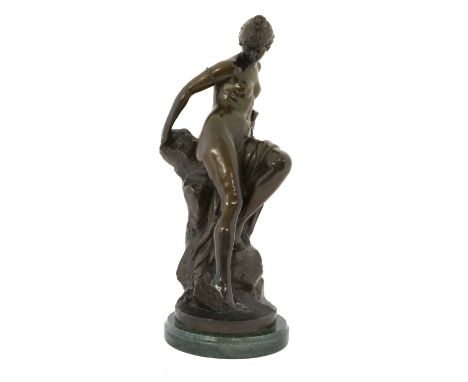 After Ferdinand Lepcke (1866-1909): A Bronze Figure of a Bather, loosely draped sitting on a rocky outcrop, on a circular bas