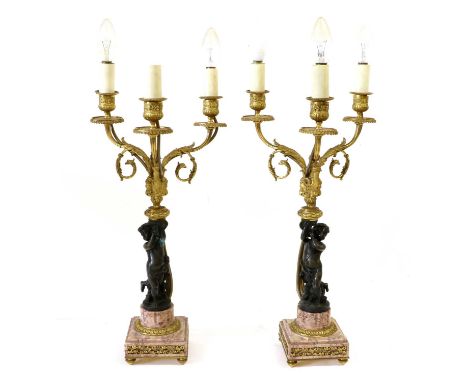 A Pair of Gilt and Patinated Bronze Three-Light Candelabra, in Louis XV style, with urn scones on leaf-scrolled branches supp