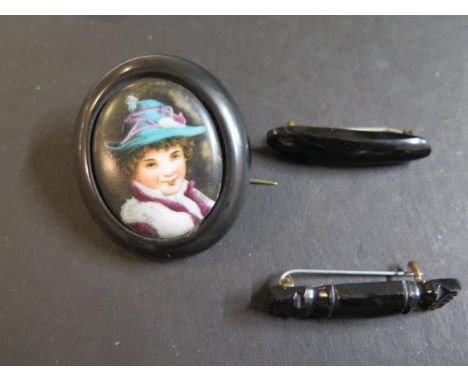 A jet oval brooch with porcelain plaque centre containing transfer printed and coloured portrait of woman and two other jet b