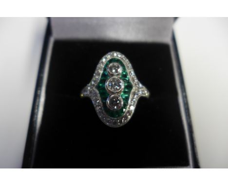 An Art Deco style emerald and diamond ring set in platinum, with three diamonds, each approx 0.18ct, surrounded by twenty-two