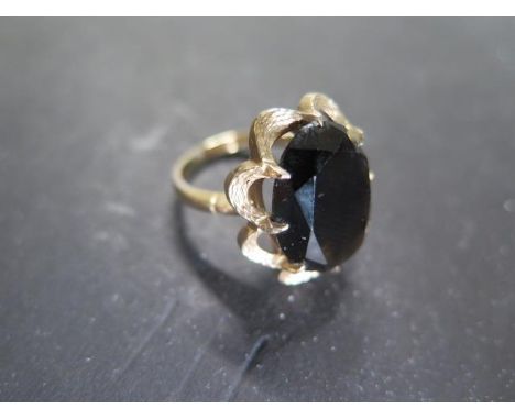 A 9ct yellow gold dress ring, plain shank to textured shoulders and bezel, set with an oval, mixed cut smoky quartz in eight 