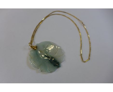 A carved jade pendant of two carp, 5cm wide, on a gold chain, 50cm long, tests to approx 22ct, approx 7 grams, generally good