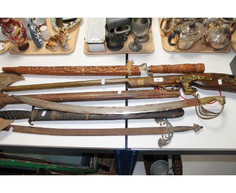 A collection of antique style weapons including Indian sabre, double headed axe, musket etc.