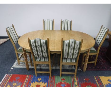 A light oak extending dining table and six chairs upholstered in striped fabric 
