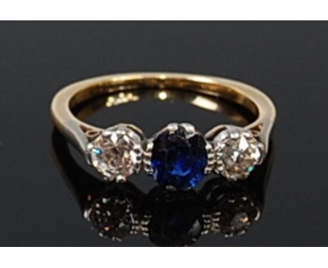 An 18ct gold, sapphire and diamond dress ring, arranged as a centre oval cut sapphire weighing approx. 0.4ct, flanked to eith