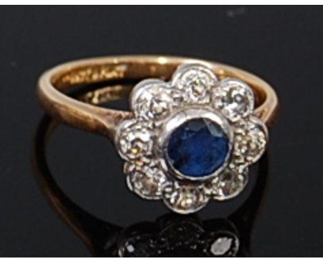 An 18ct gold and platinum, sapphire and diamond set flower head cluster ring, the centre round cut sapphire weighing approx 0