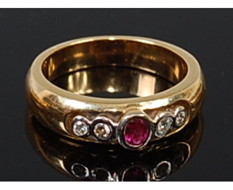 An 18ct gold, ruby and diamond ring, arranged as an illusion set oval cut ruby flanked to either side with a pair of graduate