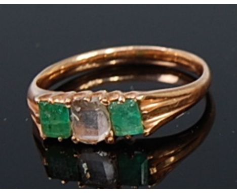 An early 20th century 14ct gold, emerald and diamond ring, arranged as a claw set square cut centre diamond flanked to either