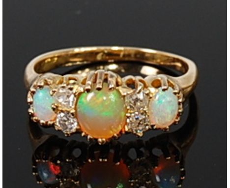 An 18ct gold, opal and diamond ring arranged as  three cabochon opals each dispersed with a pair of old cut diamonds, total d