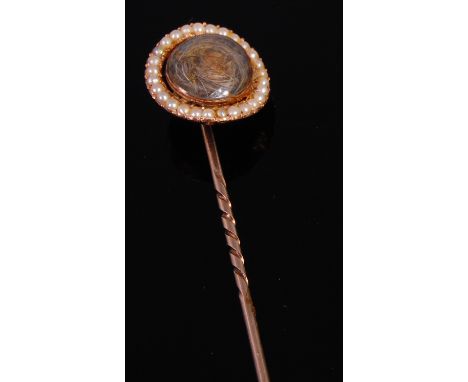 An 18th century yellow metal mourning stick-pin, set with a lock of hair under crystal, within a seed pearl set surround, dia