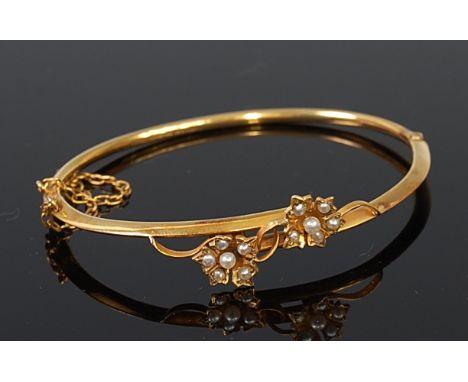 An Edwardian 9ct gold and seed pearl set hinged bangle, with safety chain, 5.1g, dia. 6cm, in original leather fitted retaile