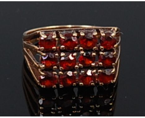 A 9ct gold and garnet set tablet ring, arranged as three rows of four round cut garnets, 4.5g, size N