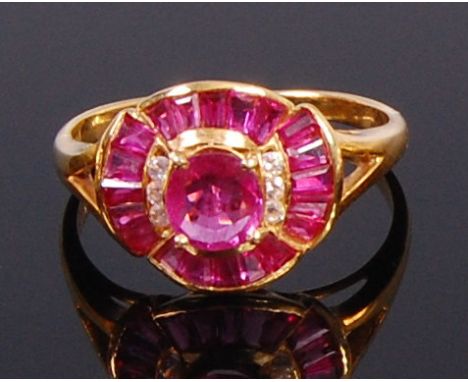 A modern 18ct gold, ruby and white sapphire cluster ring, arranged as a centre oval cut ruby flanked to either side by three 