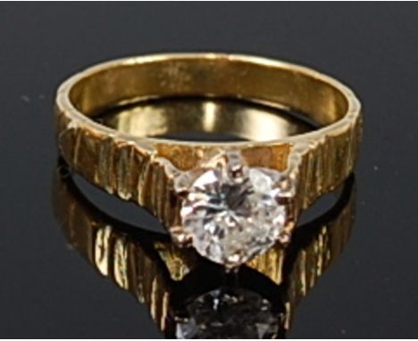 A modern 18ct gold diamond solitaire ring, the claw set brilliant weighing approx 0.65ct, to a textured shank, we would asses