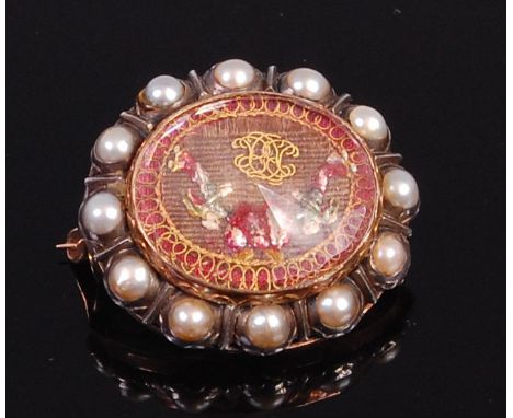 A 19th century yellow metal and seed pearl set mourning brooch, having faceted glass cover enclosing silk woven scene, all wi